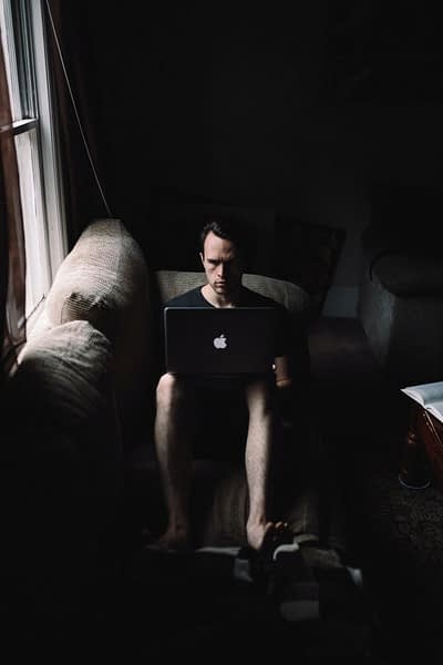 Immagine raffigurante un uomo seduto su un divano con in grembo un computer
