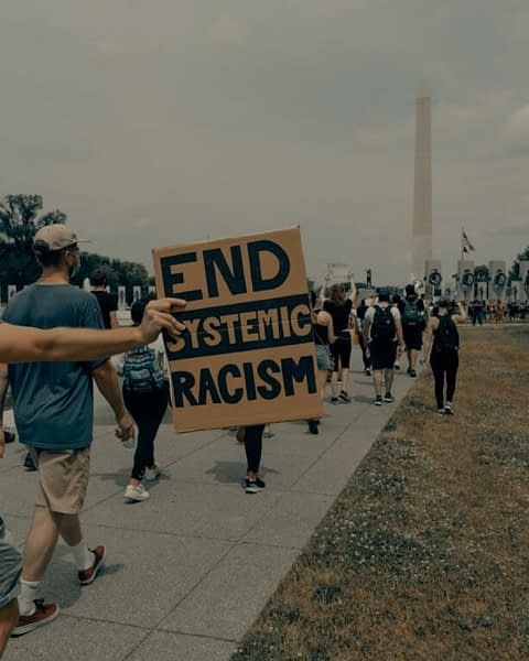 Fotografia di una manifestazione contro il razzismo, con al centro un manifesto