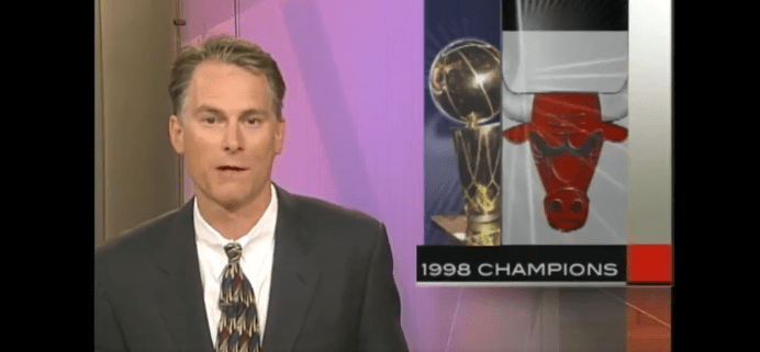 Il presentatore sportivo Kenny Mayne in giacca e cravatta sta presentando la vittoria della squadra di basket i Bulls al campionato americano del 1998 