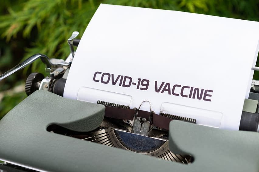 macchia da scrivere con un foglio. sul foglio c'è scritto covid-19 vaccine
